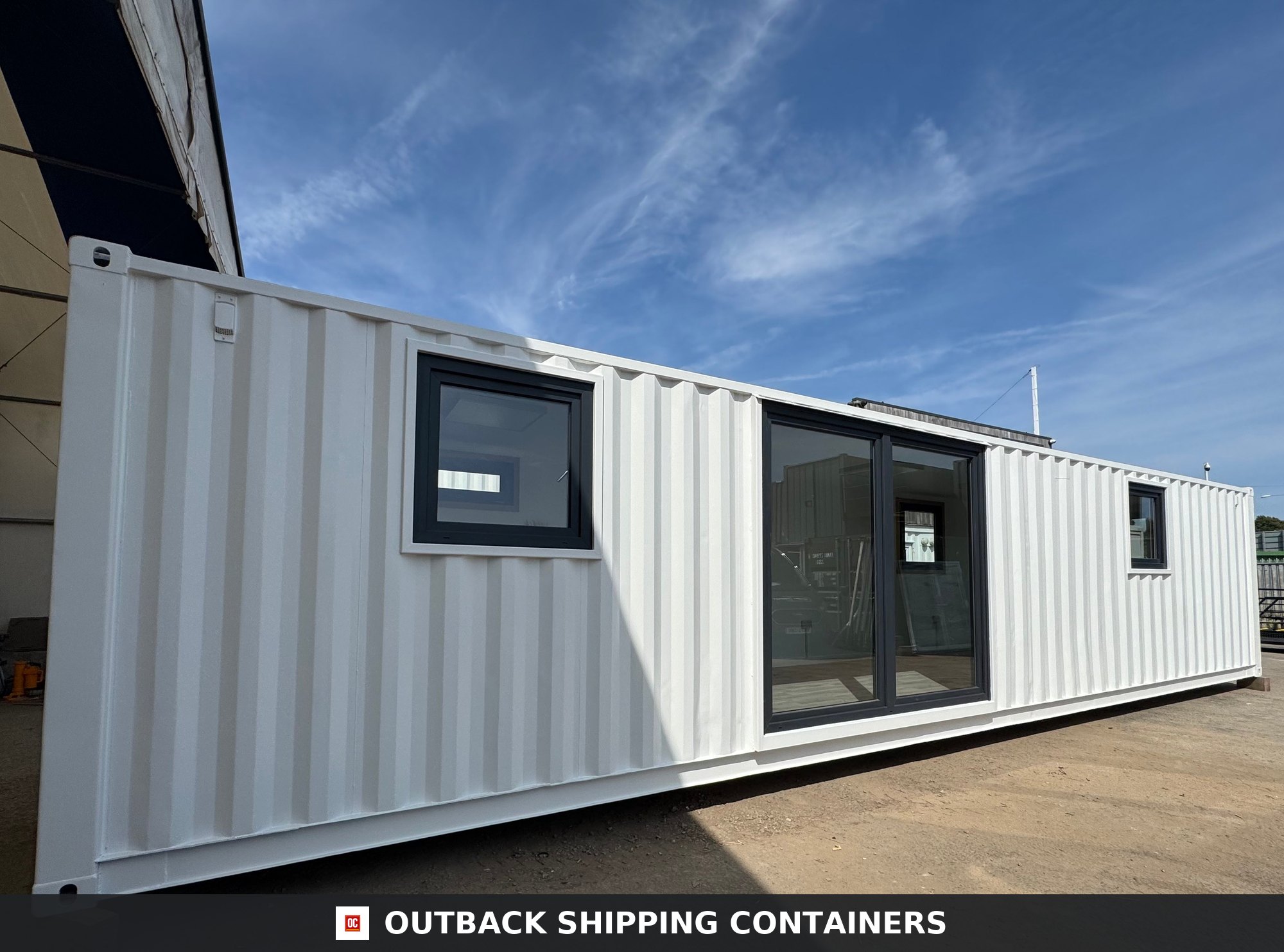 40ft white shipping container office conversion with black frame glass doors and windows under a blue sky
