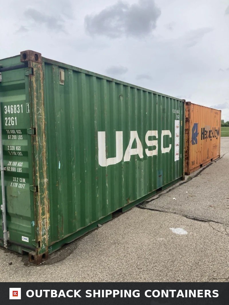 Side profile of a green UASC 20ft shipping container showing vertical steel corrugation on an outdoor asphalt lot