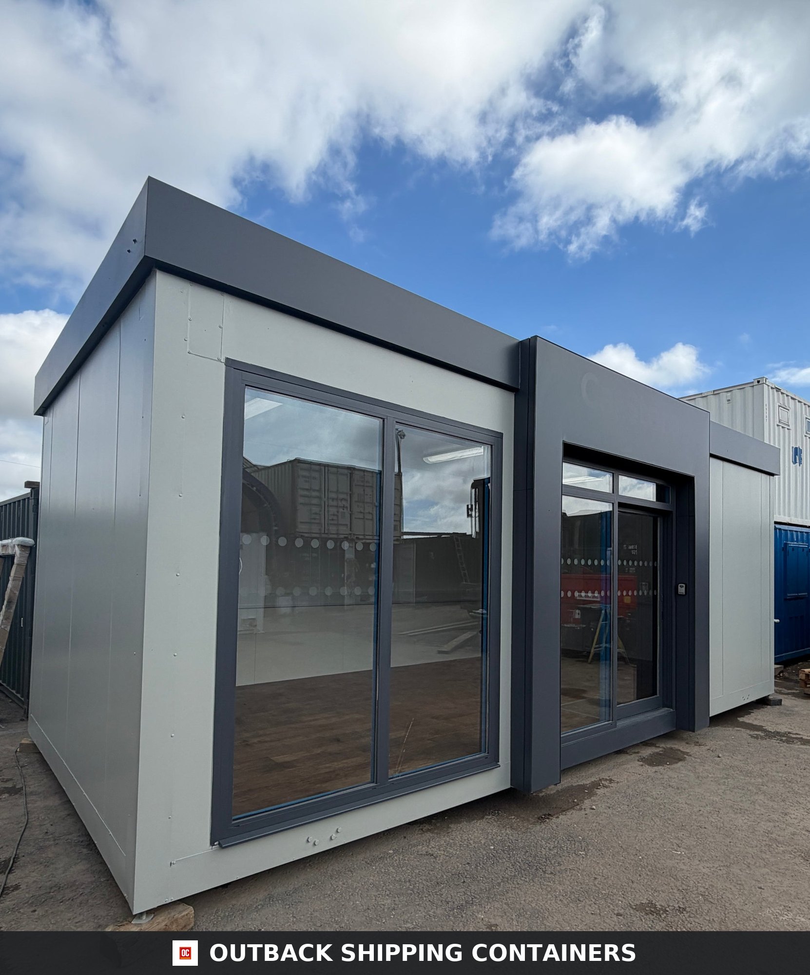 26x12ft for Sale — Corner Casting and Frame Detail | Outback Shipping Containers Modern 26x12ft marketing suite with large sliding glass windows and grey exterior trim under a blue sky