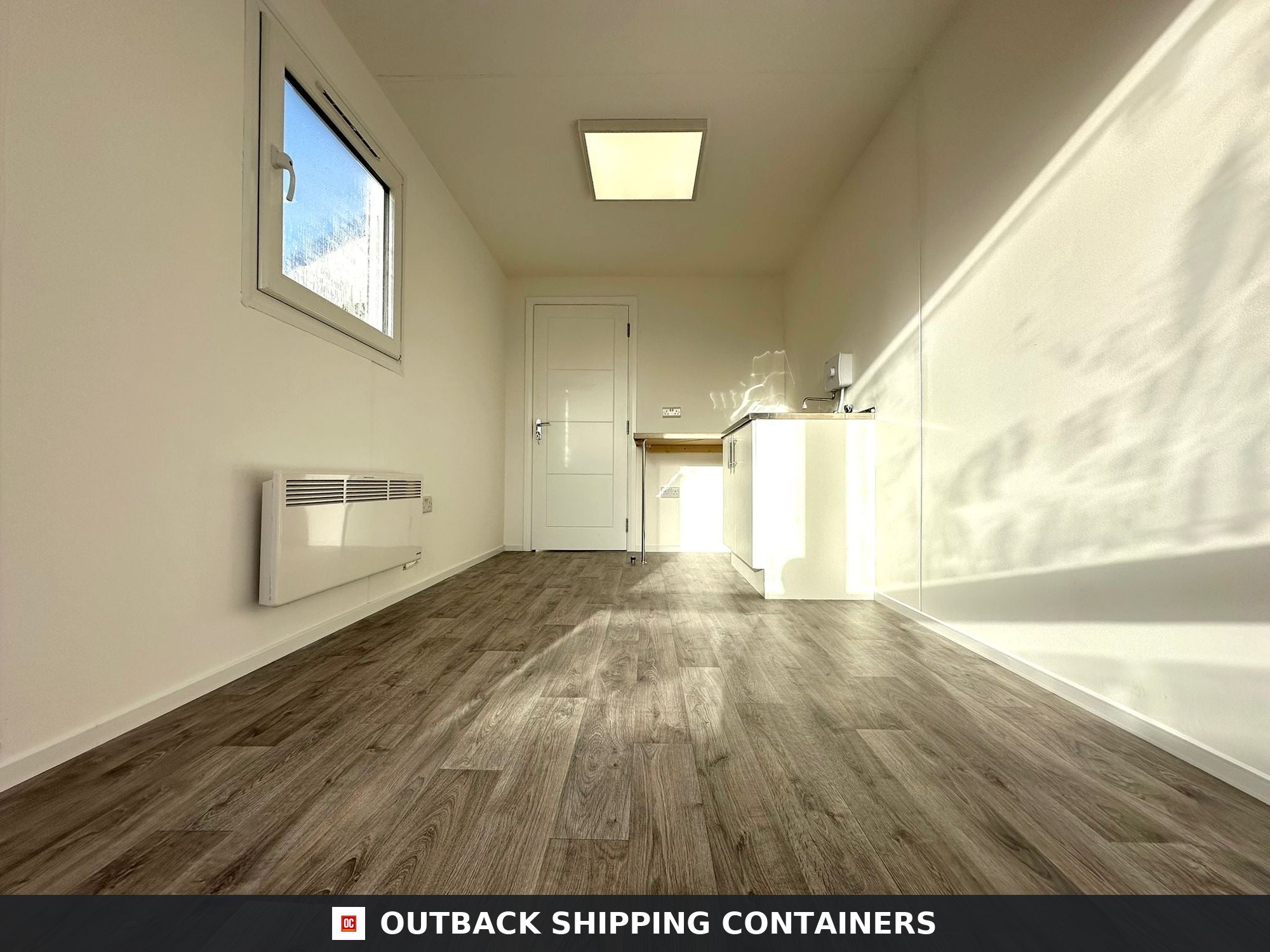 40ft shipping container office interior with wood effect flooring white walls kitchenette and window