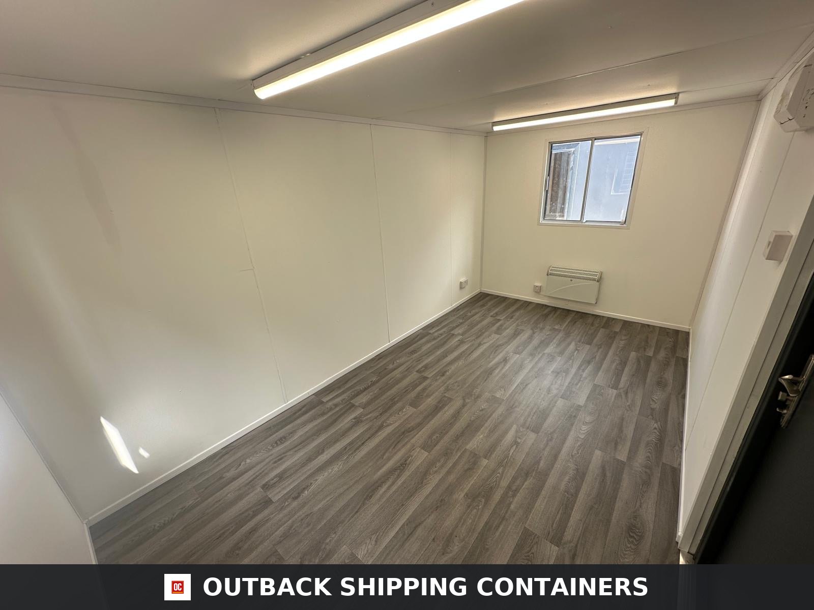 16x9 ft 16x9FT for Sale — Corner Casting and Frame Detail | Outback Shipping Containers Interior view of a 16x9ft portable office with wood-style flooring, white walls, and overhead lighting