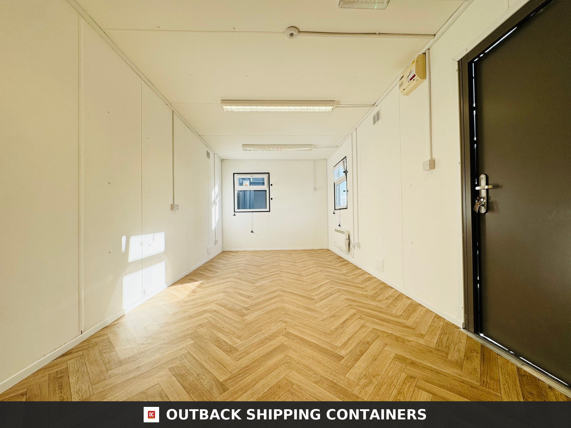 32ft Cabin for Sale — Interior View | Outback Shipping Containers 2 32ft gray anti-vandal portable cabin with white windows and steel security shutters on a dirt ground