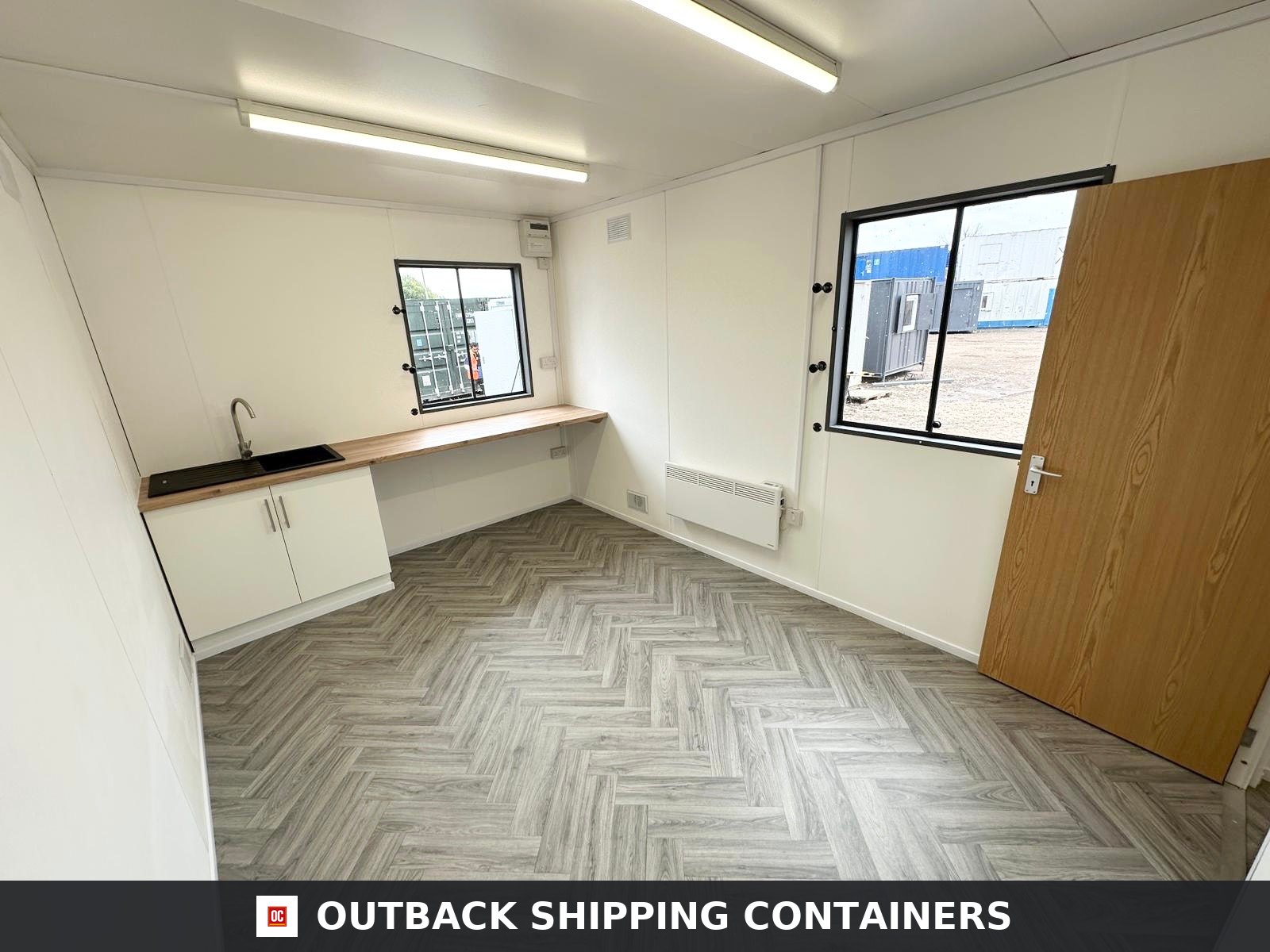 32x10Ft for Sale — Interior Detail | Outback Shipping Containers Interior view of a split office cabin featuring a small storage room and a canteen area with grey wood flooring