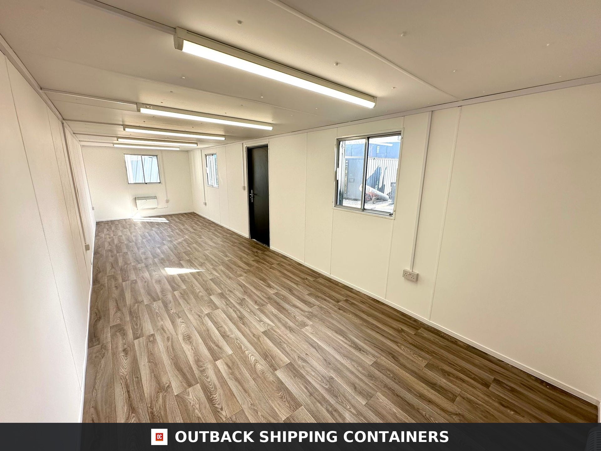 32ft Cabin for Sale — Interior View | Outback Shipping Containers 2 3 Refurbished 32ft container office interior with wood vinyl flooring, white walls, LED lighting, and windows