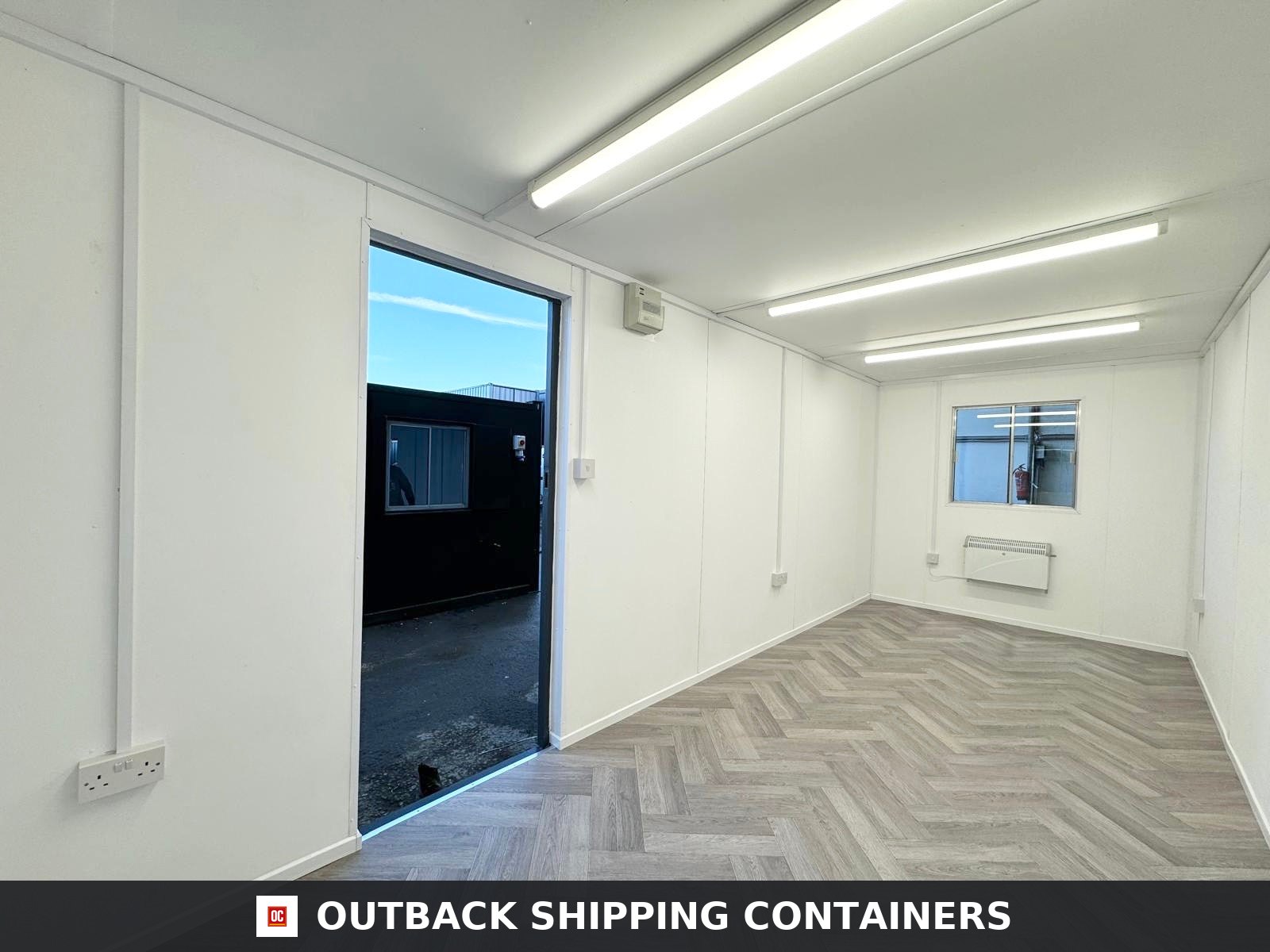 20x8ft for Sale — Roof and Structural Detail | Outback Shipping Containers Full view of a dark gray 20ft shipping container office with a steel door and grilled window shutters