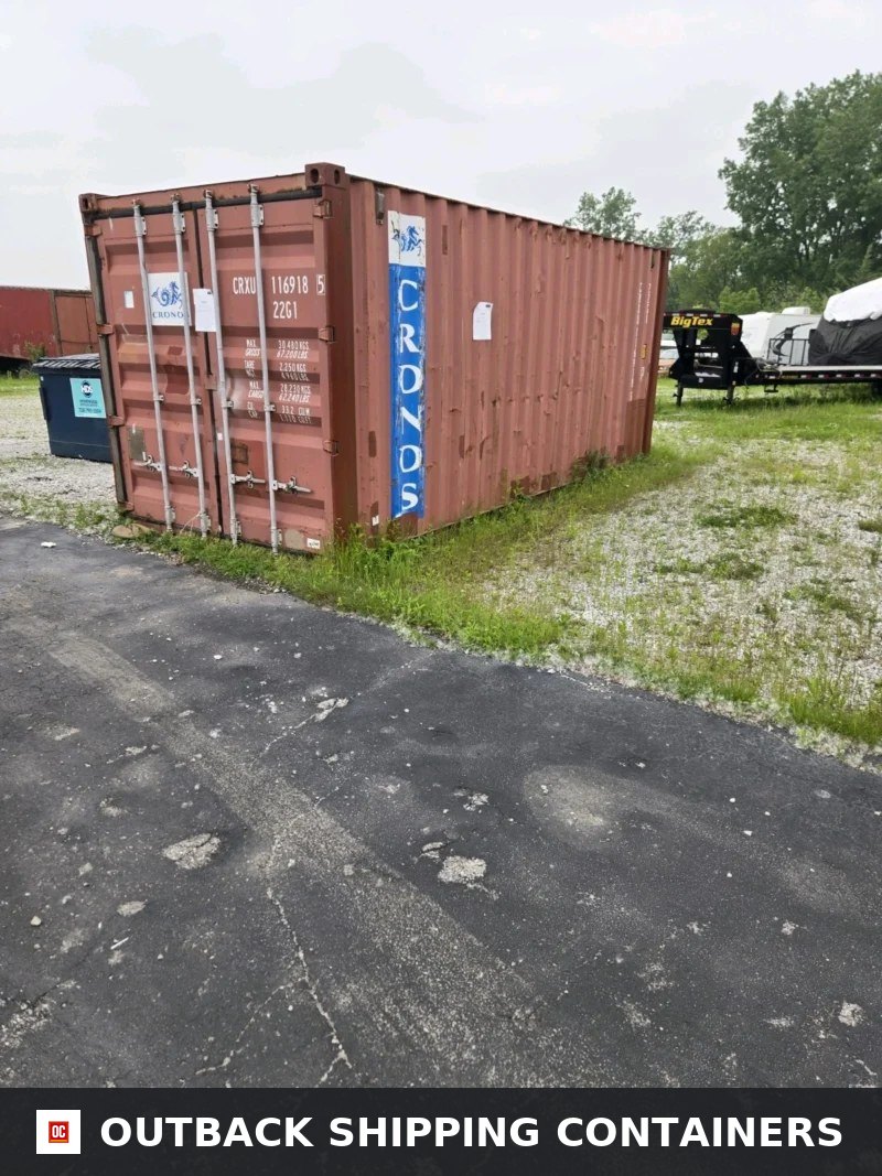Used 20 foot red storage container with double cargo doors sitting on a gravel lot near an asphalt road
