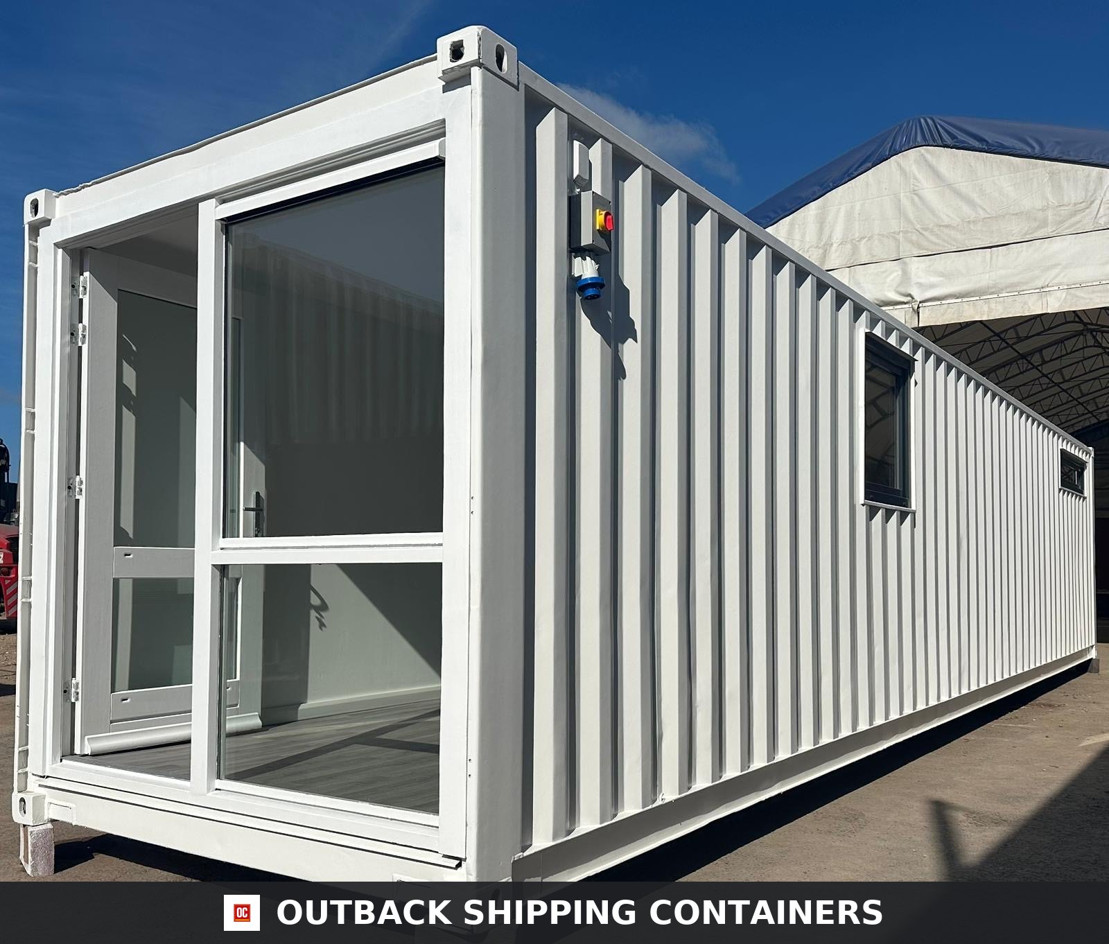 40ft white converted shipping container office with large glass entrance and side windows under a clear blue sky