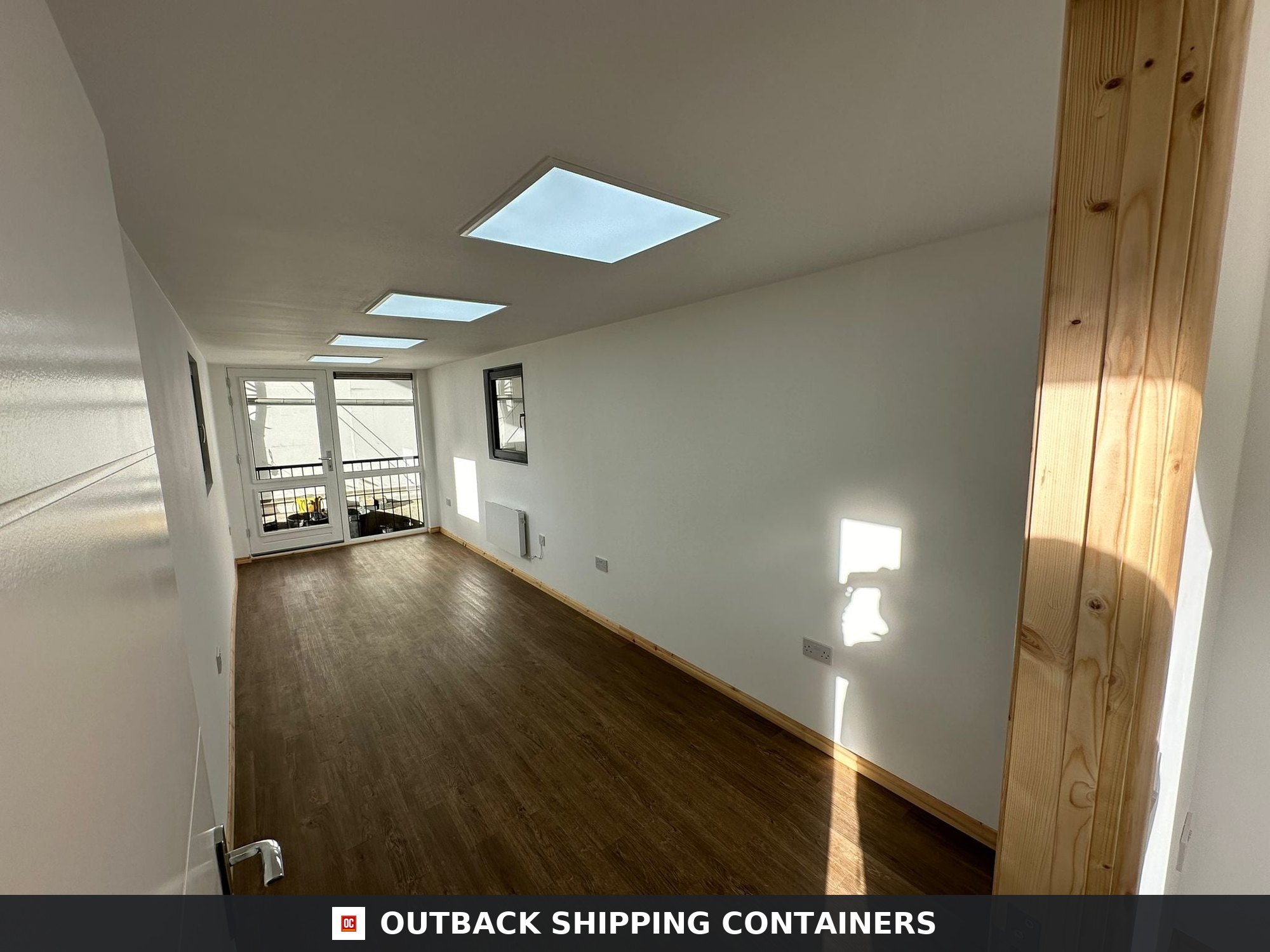 40ft shipping container office interior with wood floors, white walls, and square LED ceiling lights