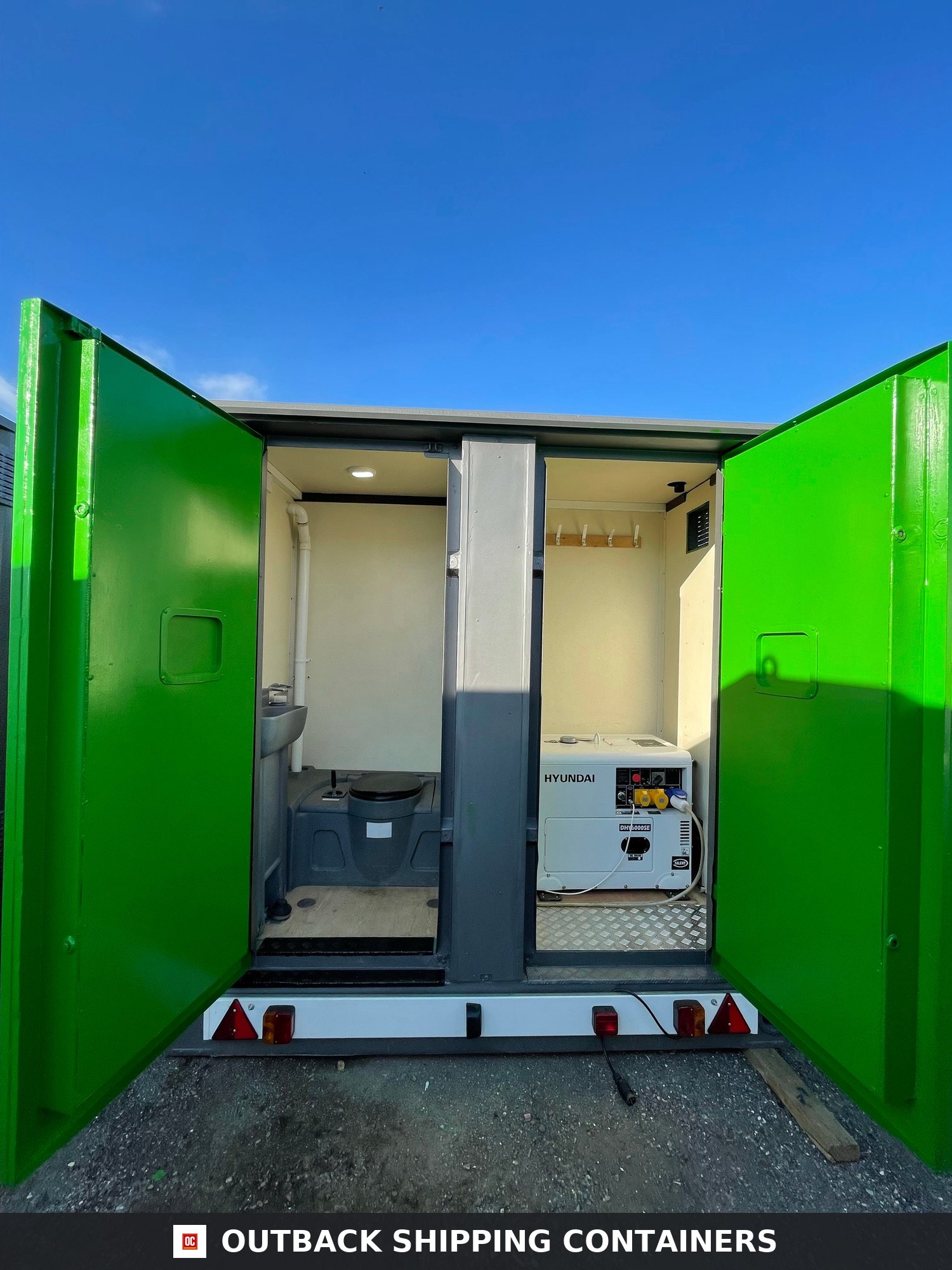 Towable Groundhog Mobile Welfare |Towable Canteen, Office, WC, Drying — Door and Entry Detail Rear view of a green mobile welfare unit with open doors showing a portable toilet and a Hyundai generator