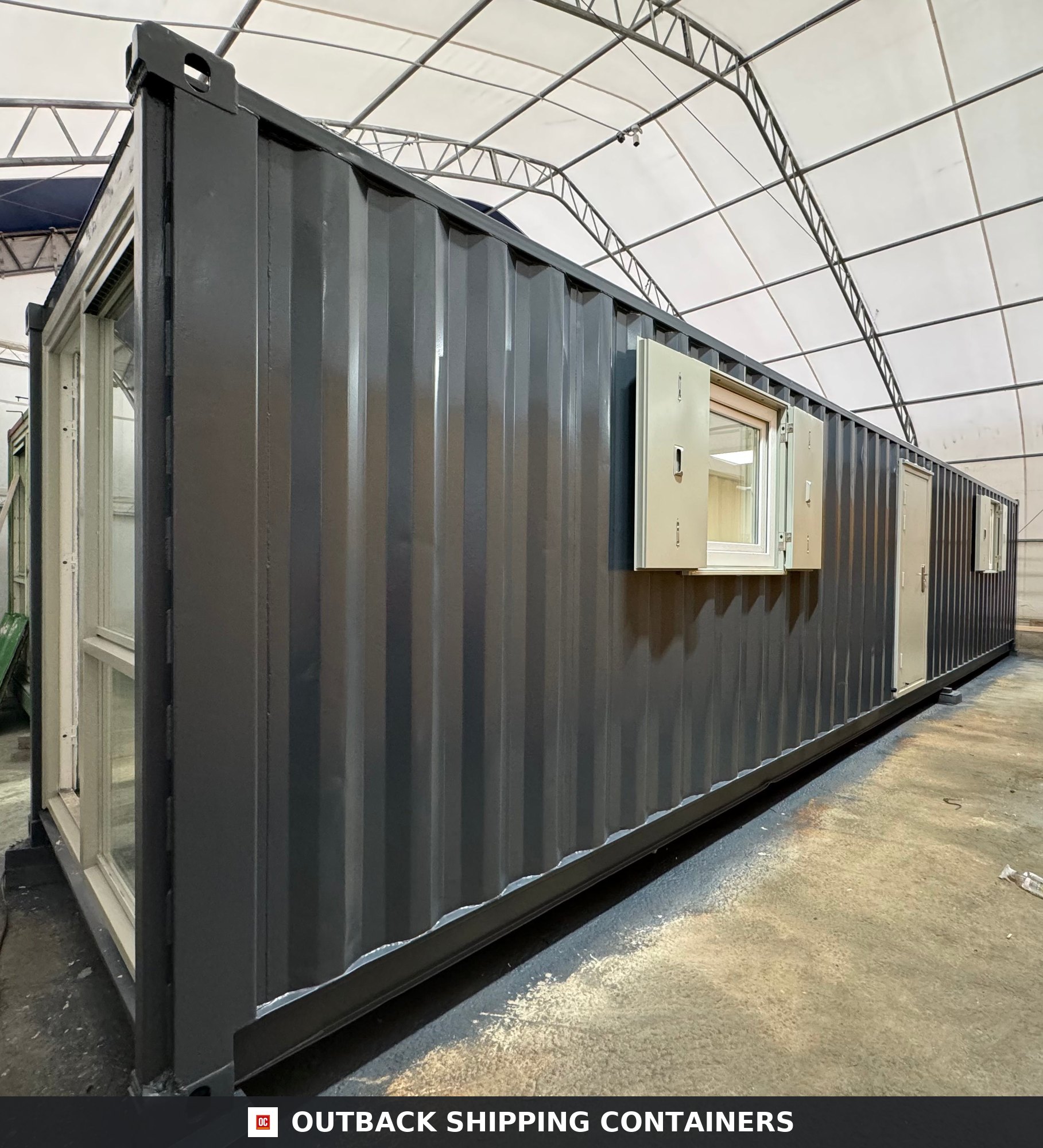 40ft refurbished container office in dark gray with side windows and glass door entry under a tented facility