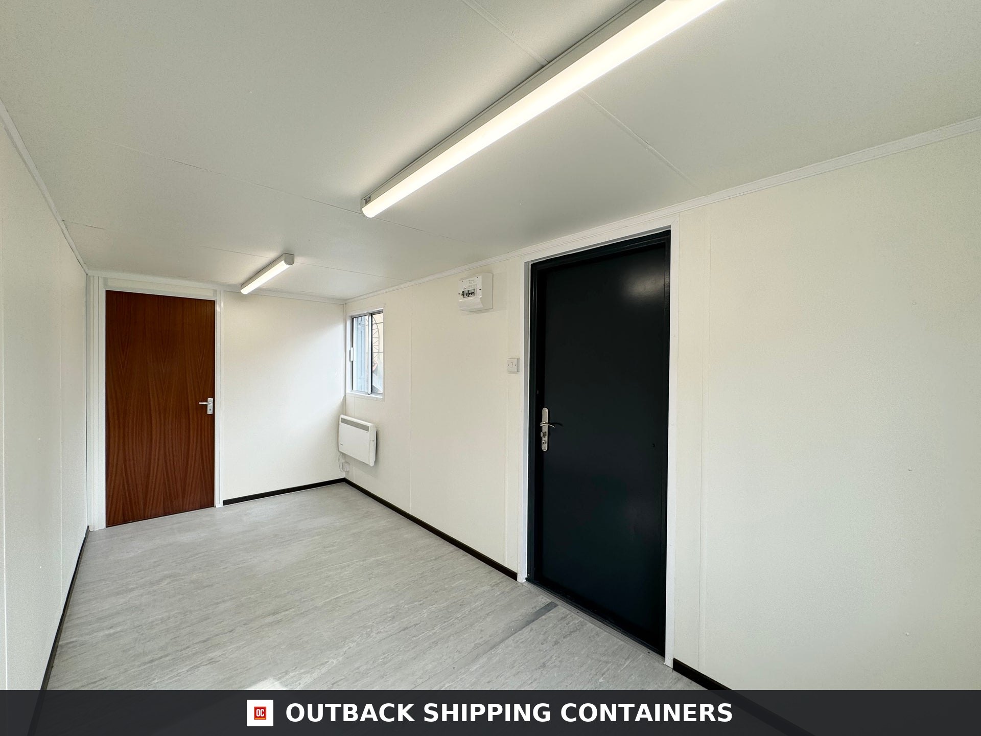 21x8ft for Sale — Door and Entry Detail | Outback Shipping Containers 2 Refurbished 21x8 storage container office interior with white walls, fluorescent lighting, and a black exit door