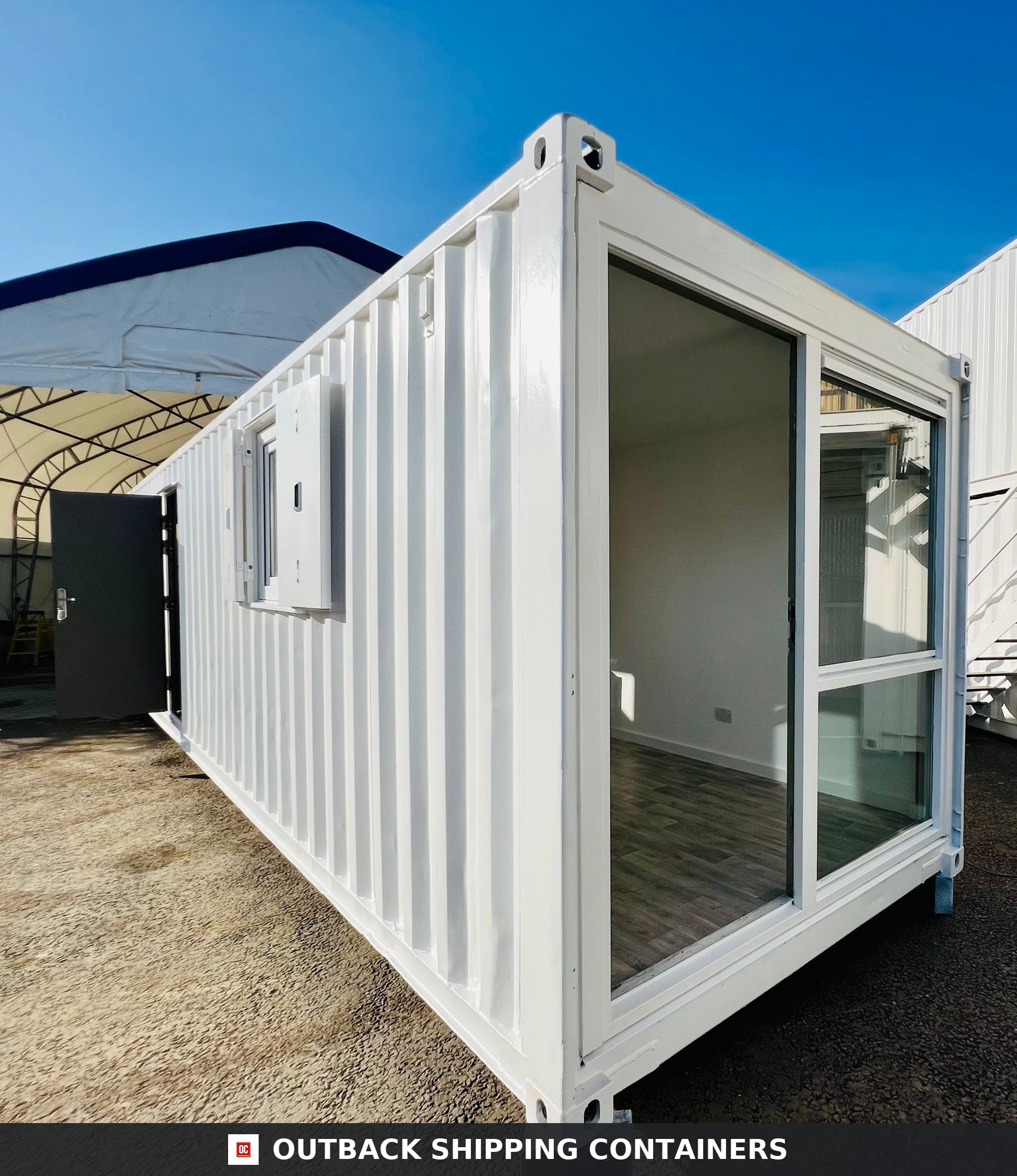 40ft white converted shipping container office with sliding glass doors and side windows on a gravel lot