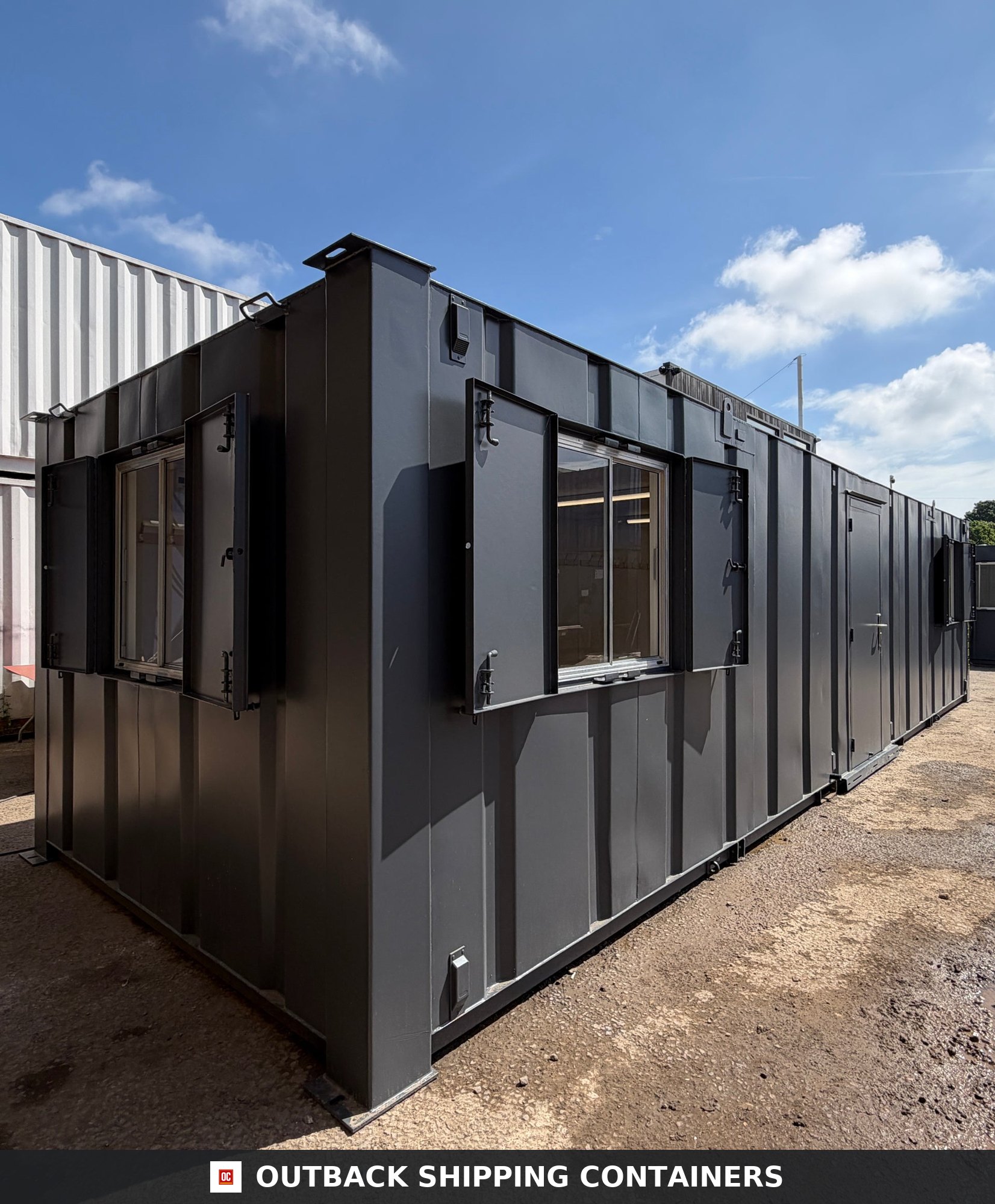 32x10ft Cabin for Sale — Interior View | Outback Shipping Containers 2 3 4 Dark grey 32x10ft anti-vandal portable cabin with steel shutters open showing glass windows outdoors