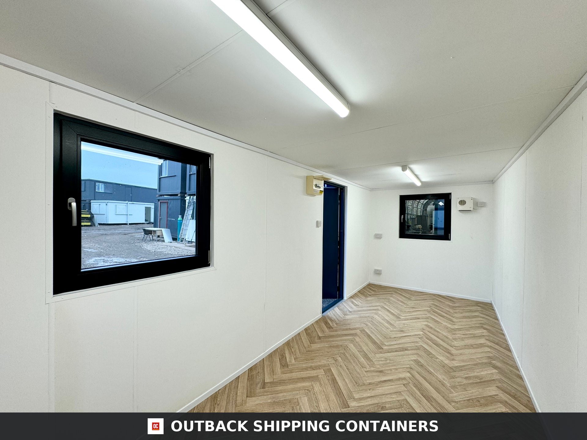 21x8ft Office Container — Corner Casting and Frame Detail | Outback Shipping Containers Side profile of a dark grey 21x8ft portable office container with a steel door and window protected by shutters