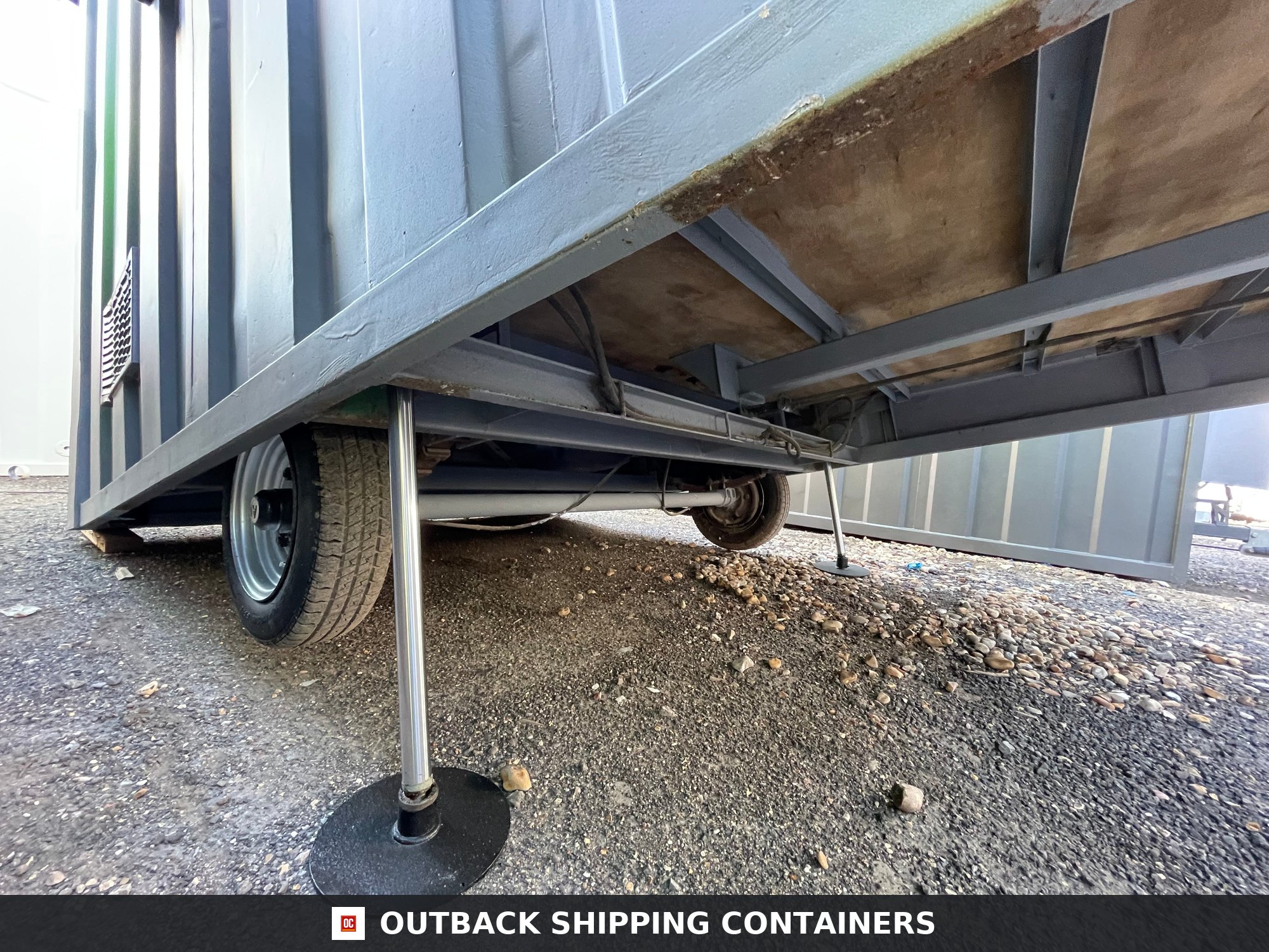 Towable Groundhog Mobile Welfare |Towable Canteen, Office — Corner Casting and Frame Detail Underside view of towable groundhog mobile welfare unit showing chassis, axle, tires, and hydraulic stabilizing leg