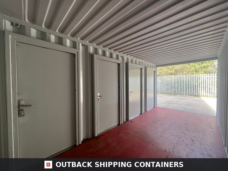 Interior view of a 20ft shipping container with four white personnel doors installed along the corrugated steel wall