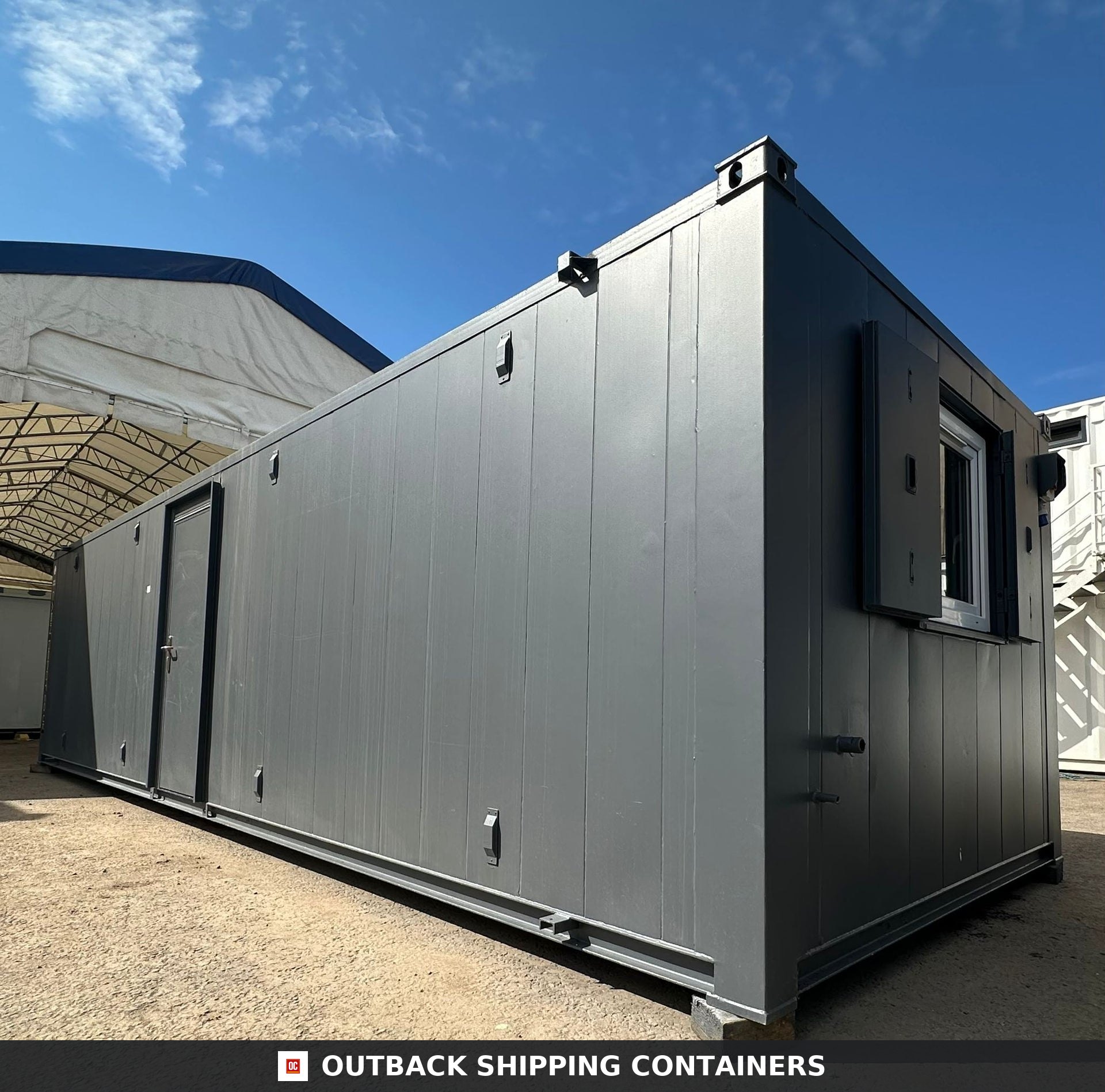 Side profile of a 32x10ft refurbished grey anti-vandal portable cabin with personnel door and window shutters