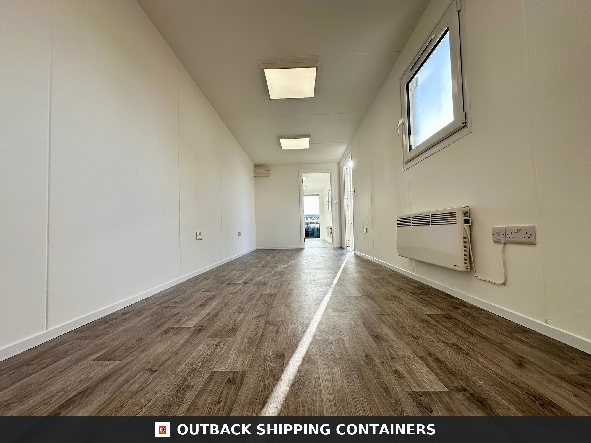 40ft refurbished shipping container office interior with wood-effect flooring white walls and ceiling lights