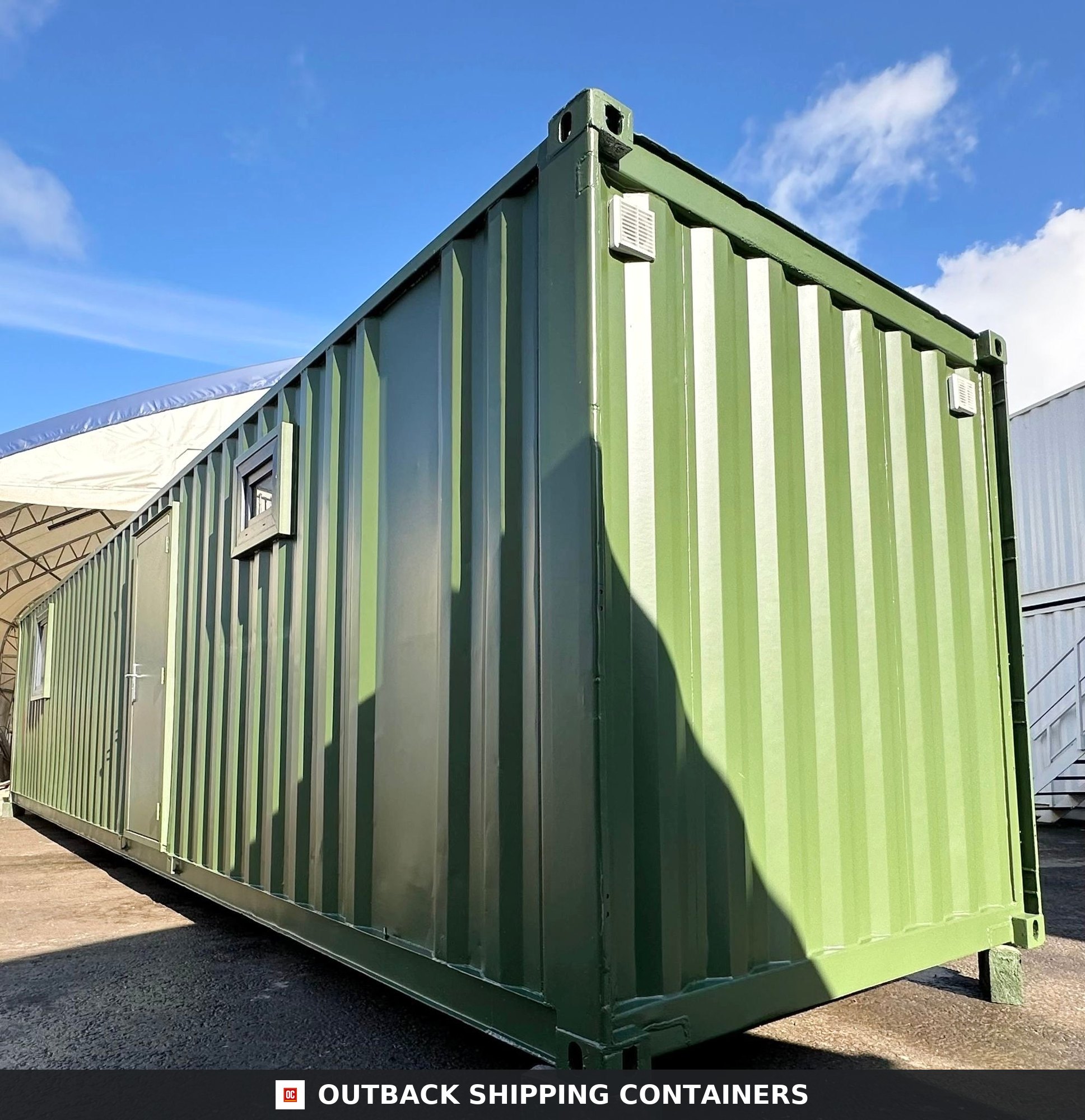 40ft green shipping container office with steel personnel door and small window under a clear blue sky