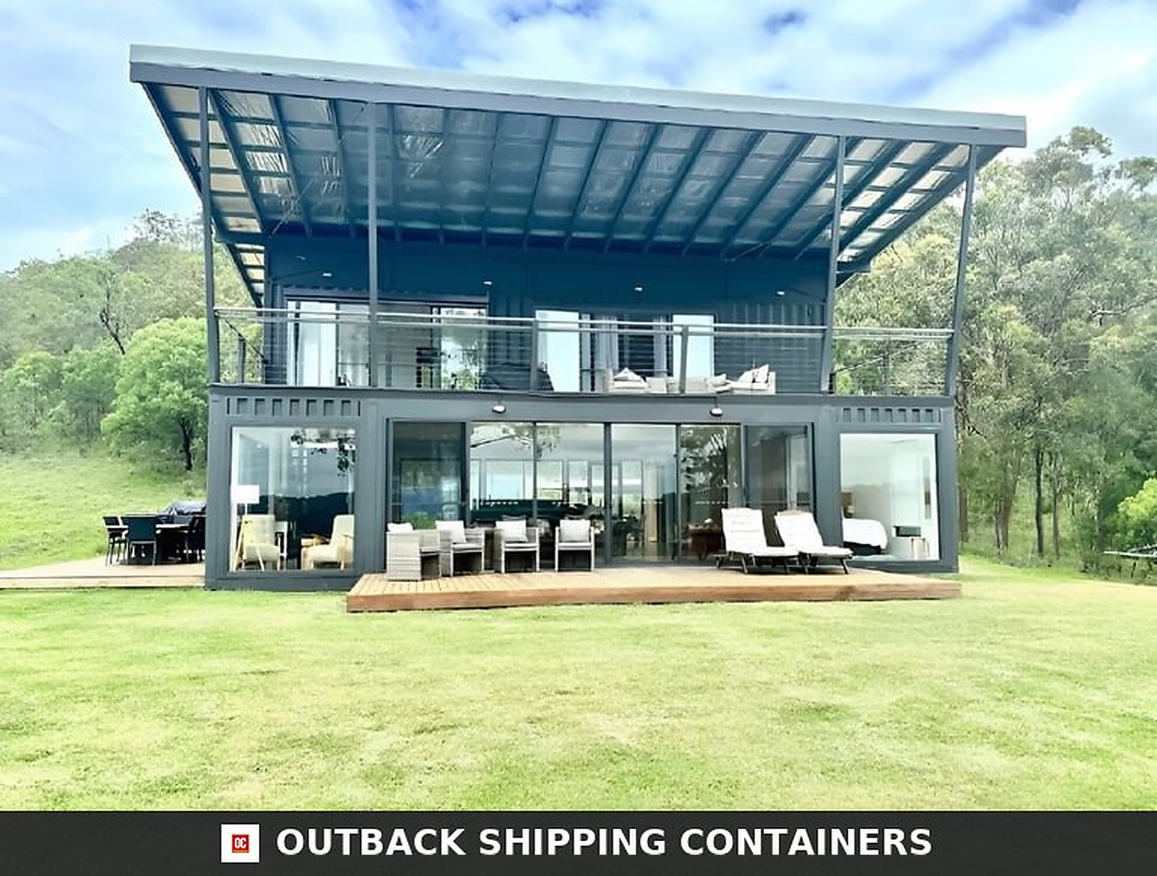 Front elevation of the two-storey 3 bedroom container house showing full-height glass walls, upper terrace and steel balustrade