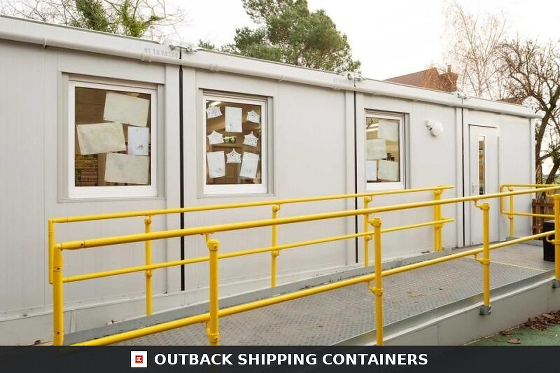 Exterior of a six-bay Euro modular building featuring a metal accessibility ramp with bright yellow handrails