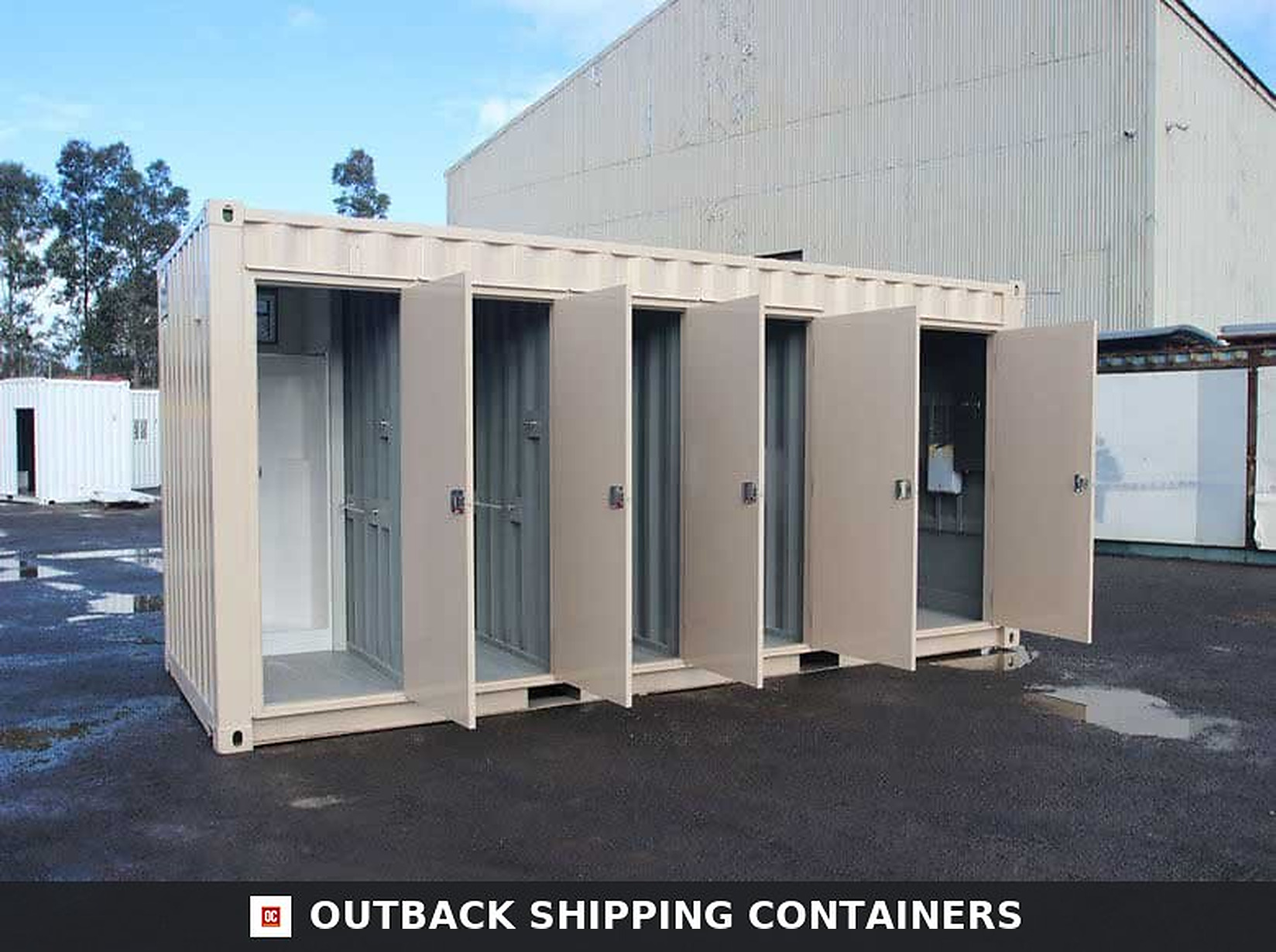 Tan ablution block container with five open stall doors showing shower and toilet cubicle interiors
