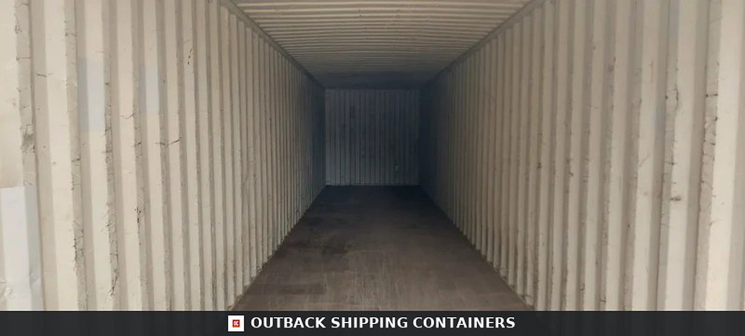 Interior view of a 40ft shipping container showing empty wooden floors and ribbed beige steel walls at a perspective angle