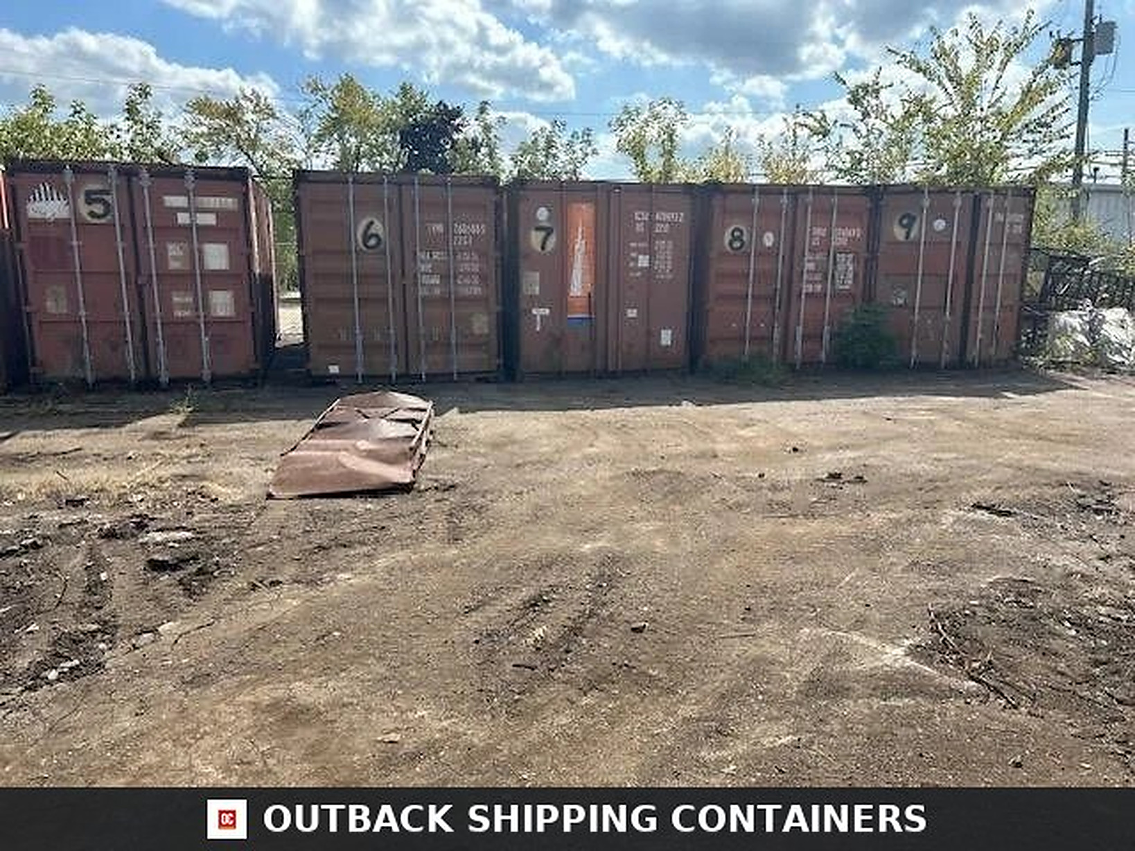Used 20′ Shipping & Storage Containers Row of five red used 20ft shipping containers numbered 5 through 9 in a dirt industrial lot under a cloudy sky