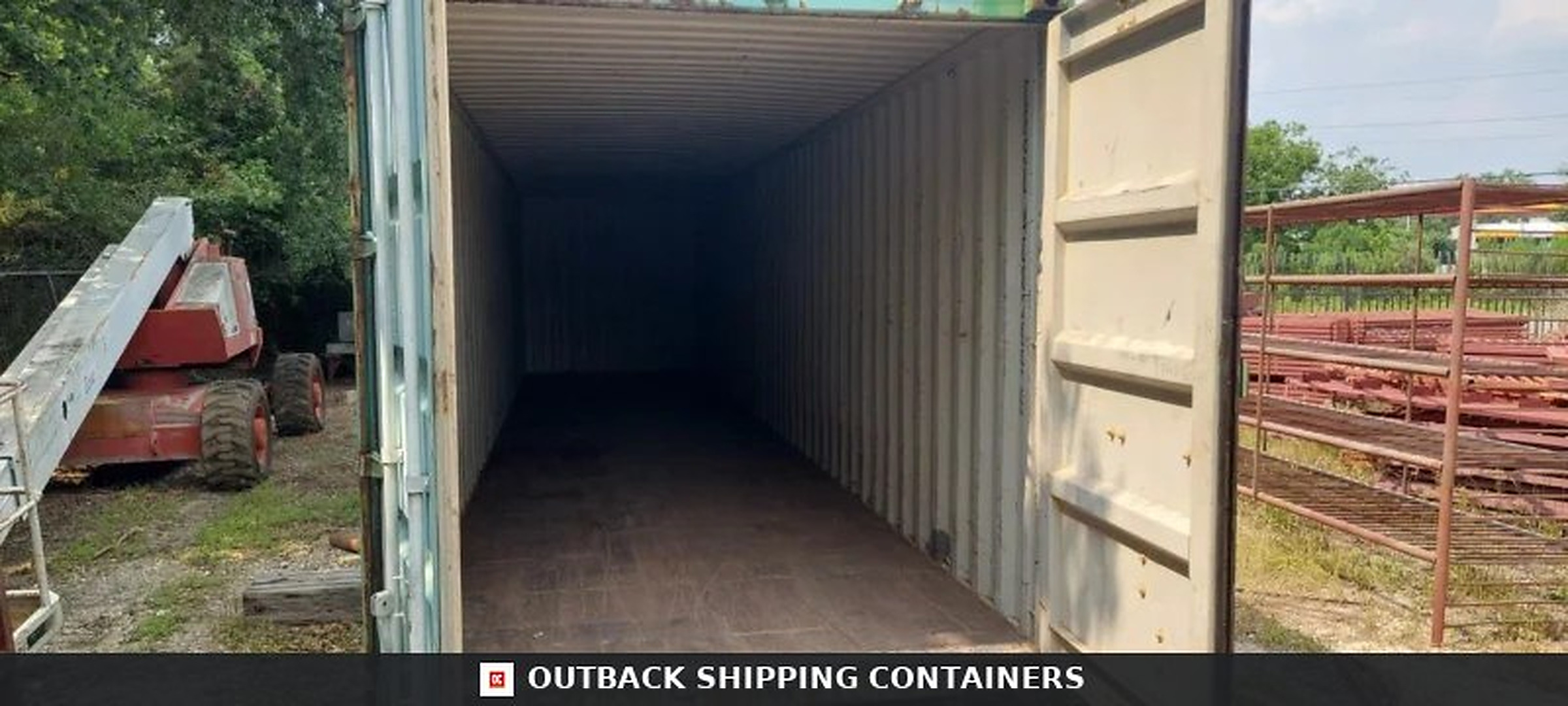 40ft shipping container interior showing dark empty space and weathered wooden flooring through an open door