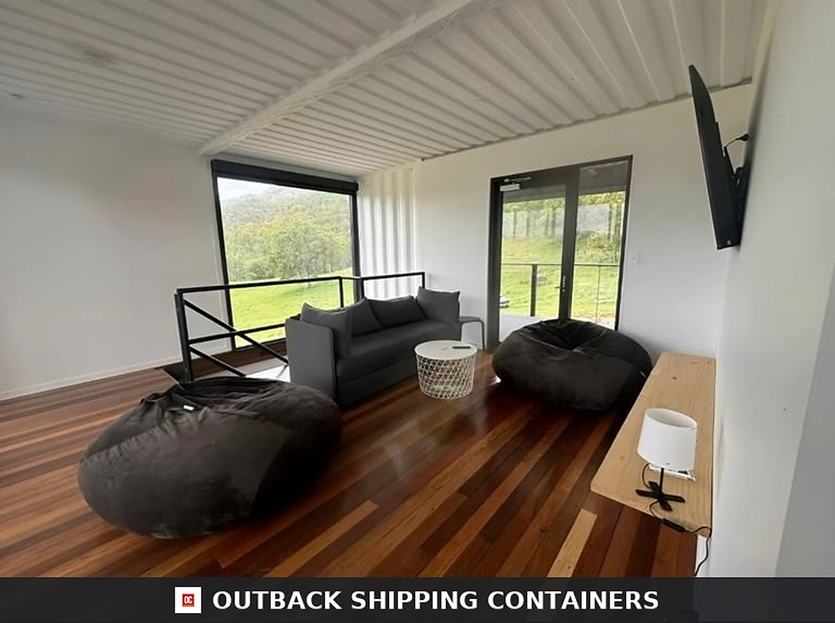 Upper level family lounge inside the 3BHK container home with sofa, bean bags and sliding glass doors to the terrace