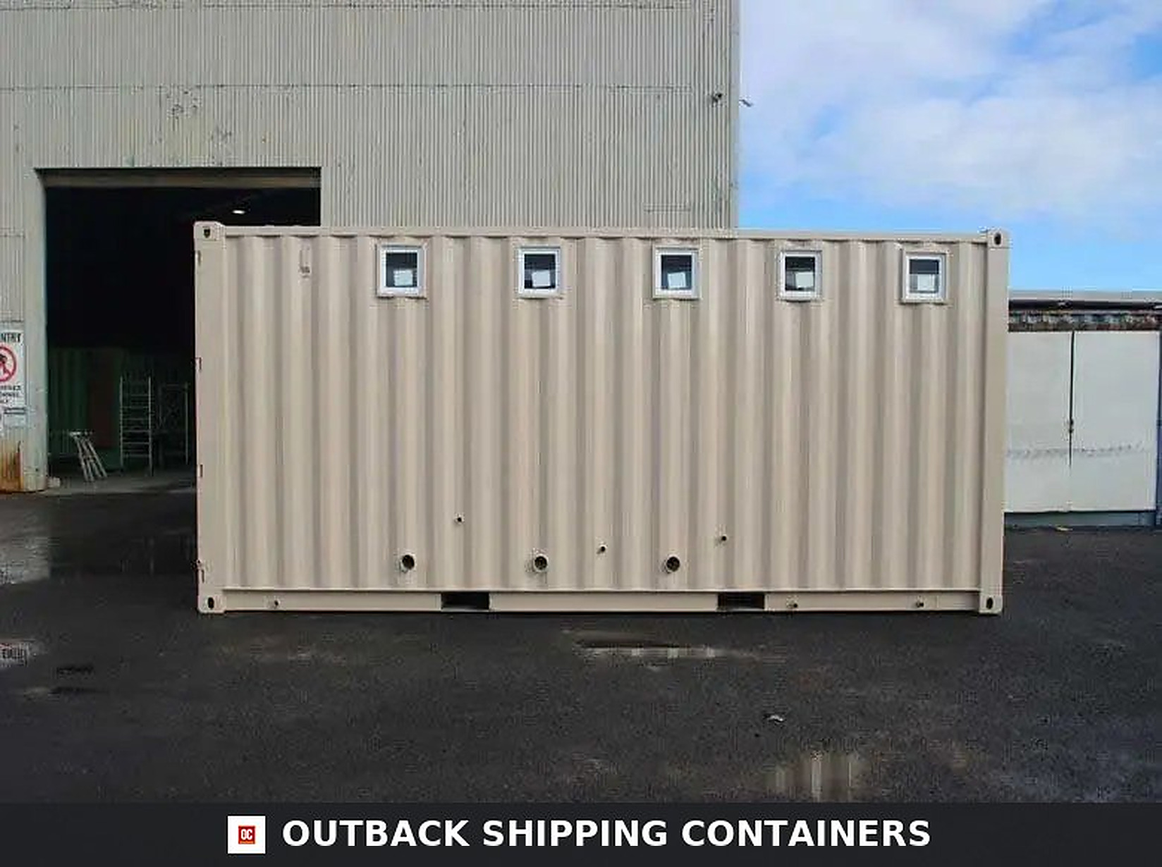 Ablution Blocks – Portable Toilet & Shower Container Units Exterior side view of a tan ablution block shipping container with five small windows and plumbing ports on the facade