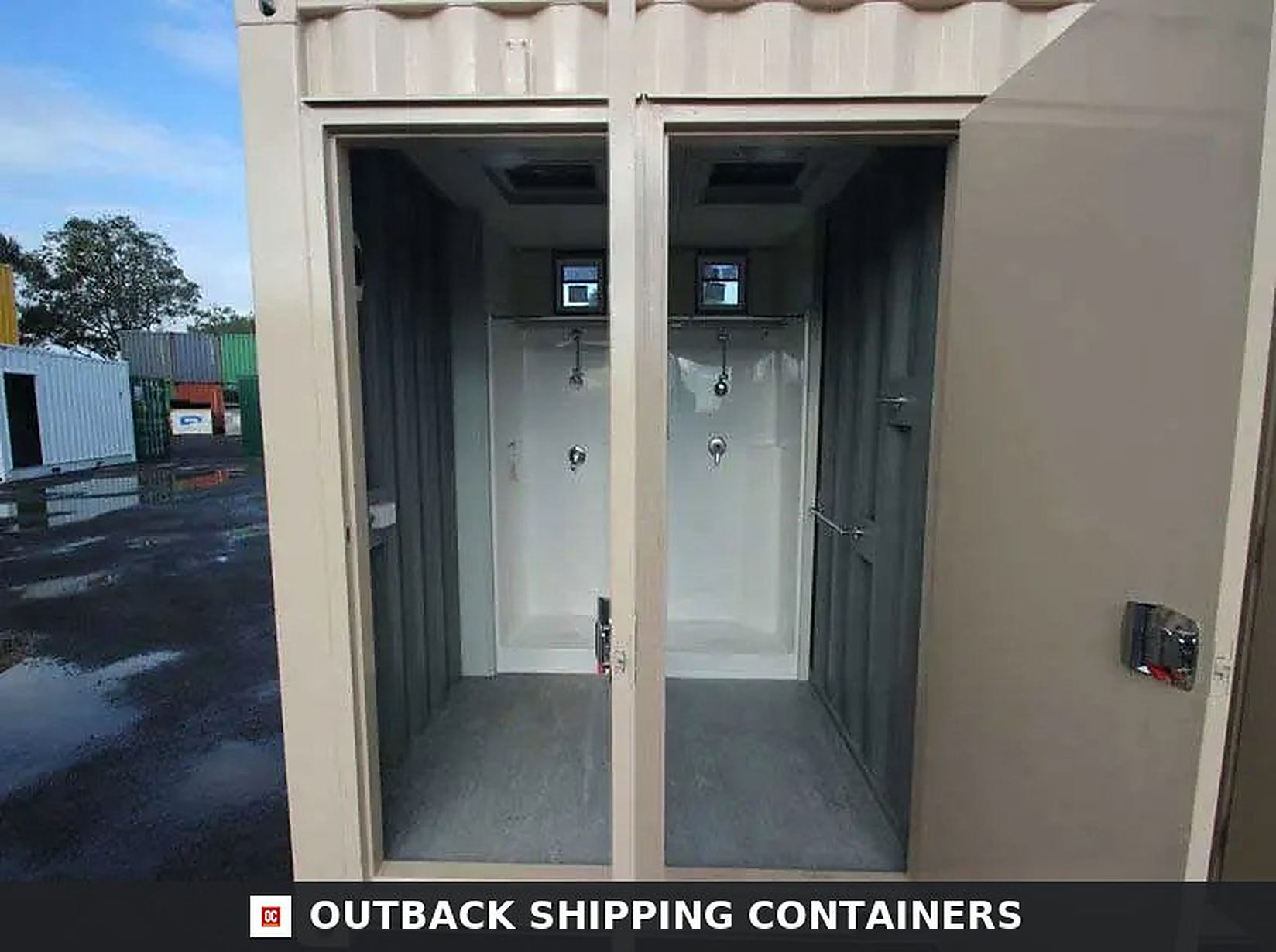 Ablution block container showing two private shower cubicles with white walls and silver plumbing fixtures