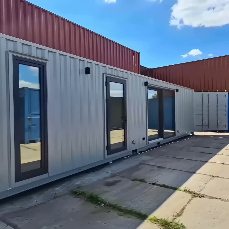 Exterior view of a custom 40ft gray shipping container home with multiple glass doors and large windows