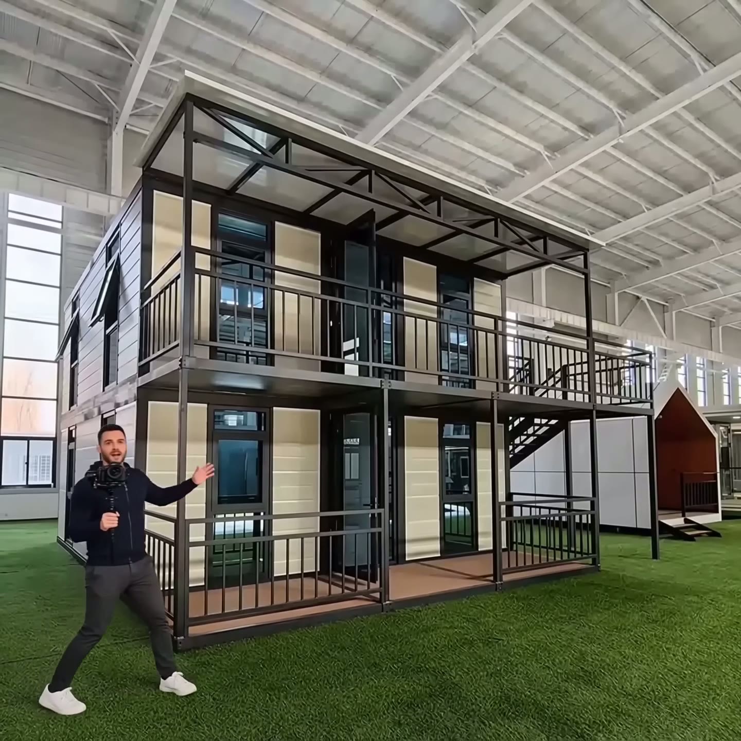 Exterior of a two-story luxury modular container villa with a full-length balcony and glass windows in a showroom